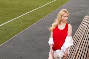 blonde avec un ballon sur le terrain de football en uniforme rouge. photo