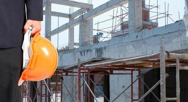 ingénieur tenant un chapeau de sécurité orange sur le fond du chantier de construction photo