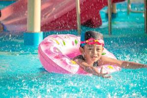 les enfants s'ébattent au parc aquatique. c'est une journée ensoleillée, parfaite pour se mouiller et jouer dur. photo