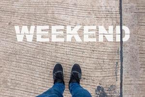 un concept de week-end, un homme porte des chaussures noires sur un trottoir en béton avec des lettres de week-end. photo