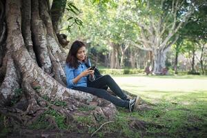 jeune femme hipster tapant sur son téléphone alors qu'elle était assise dans un parc verdoyant. photo