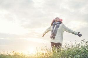 jeune fille écartant les mains et la joie avec la nature pendant l'hiver au coucher du soleil. photo