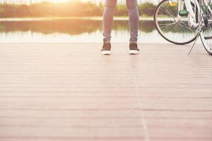 pieds de femme debout près du vélo sur le pont en bois, liberté relaxante, prêt à faire de l'équitation. photo