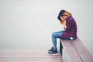 femme hipster triste assise sur la jetée avec tristesse. photo