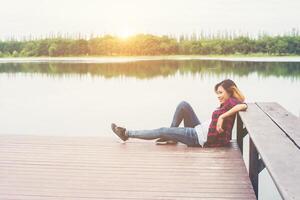 jeune femme hipster assise sur une jetée en bois, relaxante. photo