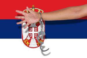 menottes avec la main sur le drapeau de la serbie photo