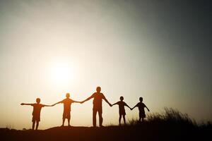 silhouette d'enfants heureux main dans la main et temps heureux avec le coucher du soleil. photo