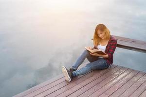 jeune belle femme hipster relaxante assise sur un livre de lecture de jetée. photo