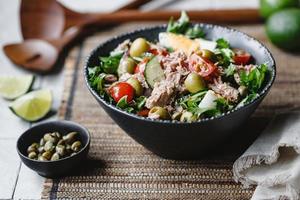 salade de thon en conserve avec légumes frais, câpres et olives dans un bol noir