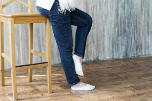 jambes en jeans sur la chaise haute de la fille enceinte. photo