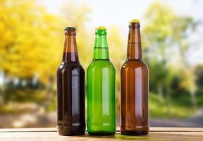 bouteilles de bière sur une table en bois sur fond de parc flou photo