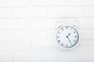 réveil rétro avec vingt-cinq minutes après une heure près du mur de briques sur le lieu de travail blanc. mise au point sélective photo