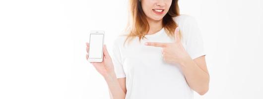 portrait recadré de femme heureuse et souriante, fille en t-shirt montrant l'écran vide de son smartphone isolé sur fond blanc. copie espace photo