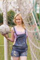 la fille avec le ballon à la porte sur le terrain de football. photo