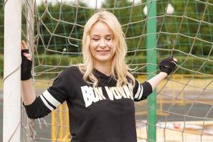 belle blonde dans la grille de football tient et sourit. photo