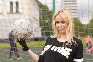 belle blonde avec un ballon au but de football. photo