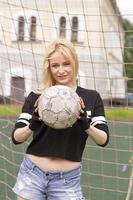 belle blonde avec un ballon au but de football. photo