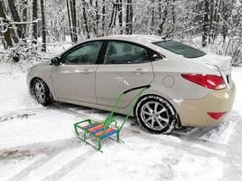 une voiture de tourisme dans la neige, garée dans un parc de la ville, sur fond d'arbres gris. photo