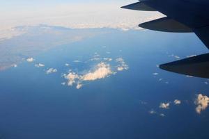 vue sur l'aile d'avion dans le ciel et la mer. concept de voyage et de transport photo