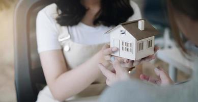 agent de courtage immobilier présentant et consultant au client pour la prise de décision signant un accord de formulaire d'assurance, modèle de maison, concernant l'offre de prêt hypothécaire et l'assurance habitation. photo