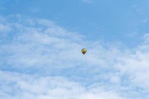 un ballon doré a volé sous le ciel bleu et les nuages blancs photo