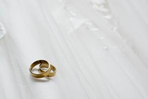 Deux anneaux de mariage portant sur la robe de mariée photo