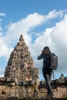 jeune femme séduisante photographe touriste avec sac à dos venant prendre des photos dans l'ancien temple phanom rung en thaïlande.