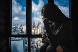 femme assise dépression debout près de la fenêtre et anxiété photo