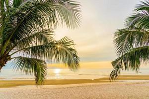 belle mer océan plage avec palmier au lever du soleil pour les vacances photo