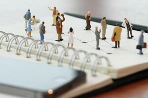 gros plan de personnes miniatures avec diagramme de réseau social sur un cahier ouvert sur un bureau en bois comme concept de médias sociaux photo