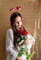 saint valentin, journée de la femme. jeune femme brune caucasienne assise dans le lit célébrant la saint valentin travaillant sur un ordinateur portable en ligne photo