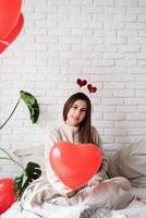 jeune femme drôle assise dans le lit célébrant la saint valentin photo