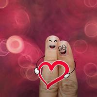 le couple de doigts heureux amoureux de smiley peint et tient le cœur sur fond de nature photo