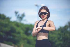 coureuse vérifiant la montre intelligente fitness tracker et souriante après le jogging et les jambes des coureurs photo