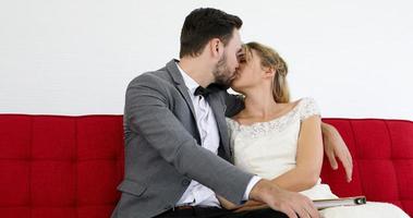 les amoureux donnent des fleurs à la mariée et s'embrassent heureux et le couple aime debout dans le studio de mariage photo