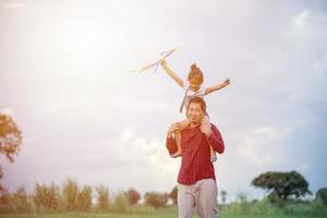 fille et père d'enfant asiatique avec un cerf-volant courant et heureux sur le pré en été dans la nature photo