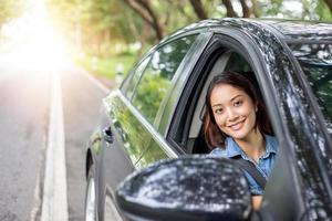 belle femme asiatique souriante et appréciant.conduire une voiture sur route pour voyager photo