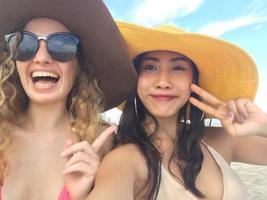 les femmes prennent des photos et des selfies avec des amis sur la plage de sable en été.