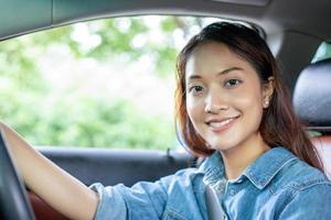 belle femme asiatique souriante et appréciant.conduire une voiture sur route pour voyager photo