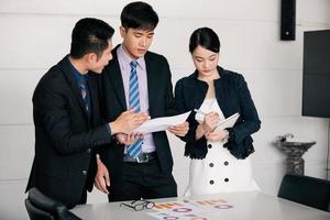 hommes d'affaires travaillant et pointant sur un diagramme financier graphique et des documents d'analyse sur une table de bureau photo