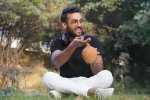 un homme assis dans le parc et met de l'argent dans la tirelire photo