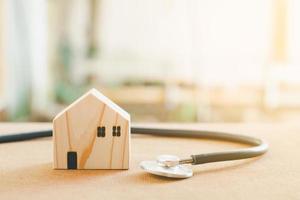 concept de réparation et d'inspecteur à domicile. stéthoscope et modèle de maison en bois. vérification de la maison et de l'immobilier avec la lumière du soleil. photo