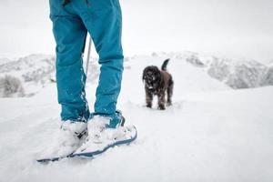 détail d'une fille en raquettes lors d'une promenade avec son chien noir photo