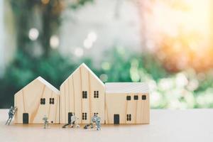 personnes miniatures ou petit modèle de figure humaine nettoyant avec une maison en bois avec un fond de bokeh de nature verte. photo