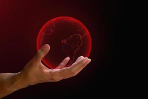 concept de crise mondiale. terre rouge transparente sur la main humaine sur fond rouge et sombre. avec espace de copie. réchauffement critique mondial, virus corona de l'homme. photo