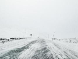 conduite à travers une tempête de neige blizzard avec de la glace noire sur la route, en norvège. photo