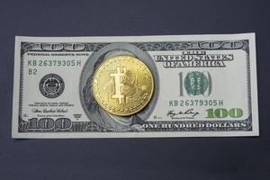 cent dollars et bitcoin sur fond noir. photo