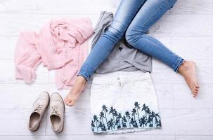 écharpe, chaussures, jupe et jambes féminines en jeans sur un plancher en bois blanc. vue de dessus