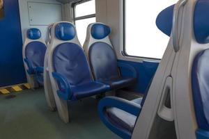 à l'intérieur de la cabine de l'express moderne. personne dans des chaises bleues près de la fenêtre. flou. chaises confortables et table au premier plan, fond blanc à l'extérieur de la fenêtre. photo