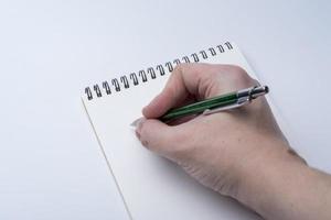 mains d'un homme tenant un cahier et un stylo sur un fond blanc. photo